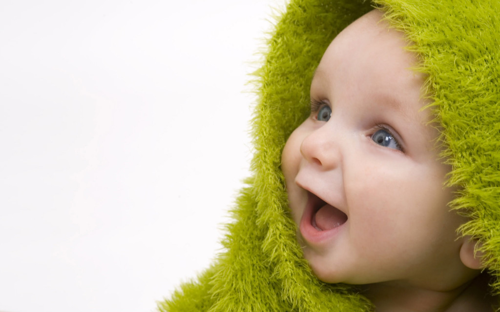 A beautiful smiling baby wrapped in a furry green blanket